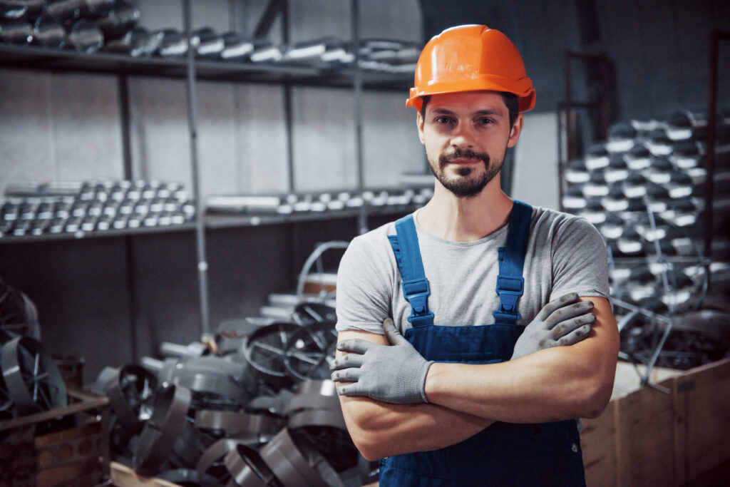 Coordinador de Contenido Digital portrait of a young worker in a hard hat at a large metalworking plant. shiftman on the warehouse of finished products